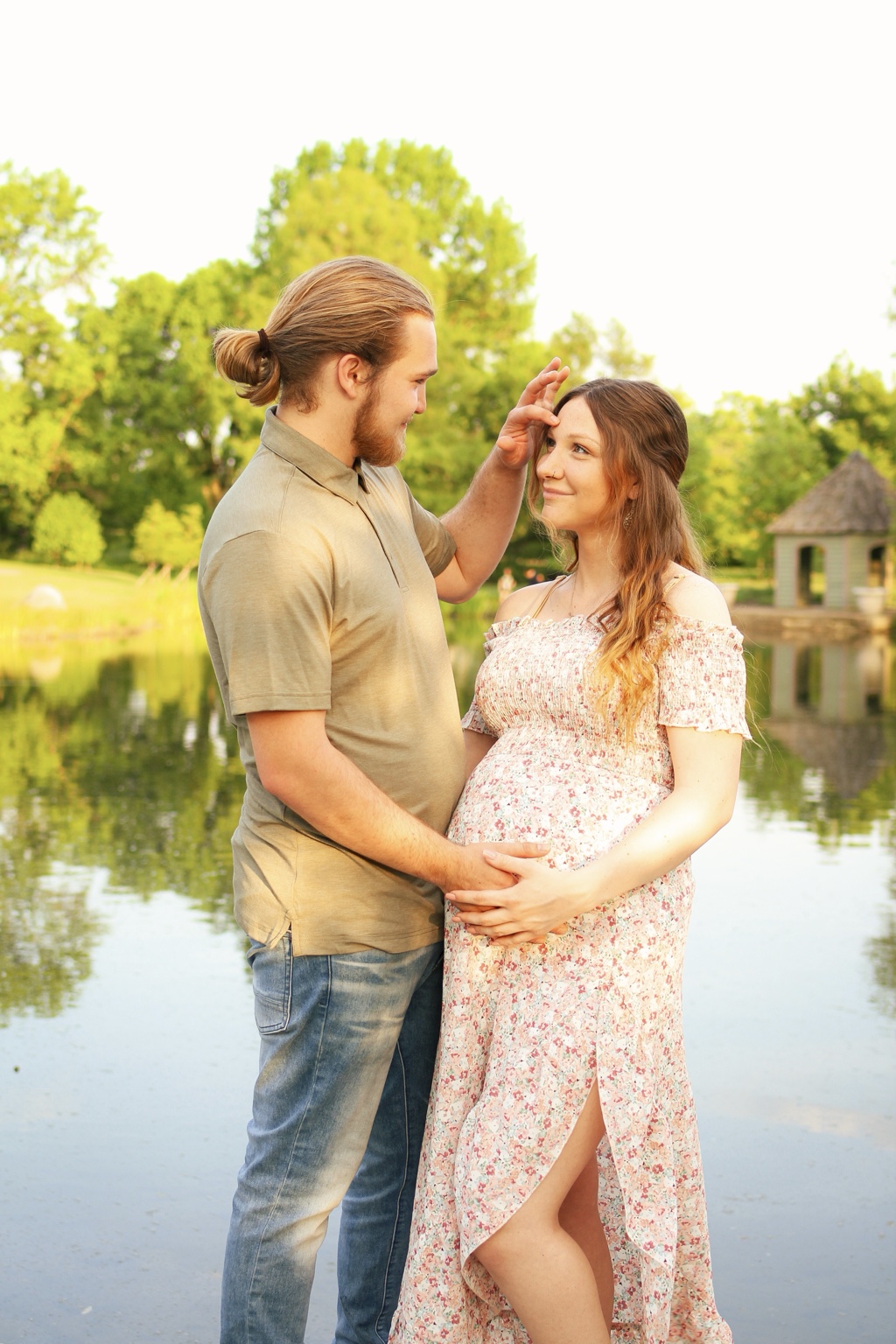Couple sharing a moment beside a pond during a maternity session